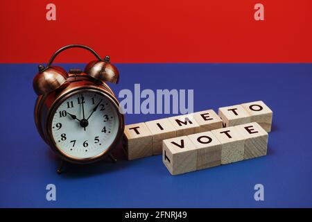 Zeit zum Abstimmen Alphabet Buchstaben mit Wecker auf blauem und rotem Hintergrund Stockfoto