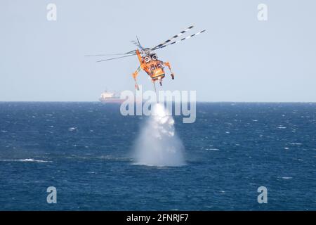 Der Erickson S64E Aircran hebt das Meerwasser durch seinen Schnorchelschlauch, um es auf einem nahegelegenen Buschfeuer in der Nähe des Lake Macquarie, NSW, Australien, einzusetzen Stockfoto