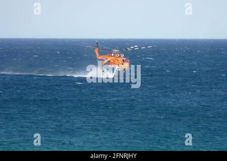 Der Erickson S64E Aircran hebt das Meerwasser durch seinen Schnorchelschlauch, um es auf einem nahegelegenen Buschfeuer in der Nähe des Lake Macquarie, NSW, Australien, einzusetzen Stockfoto