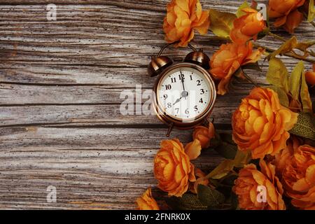 Vintage Wecker und Blumenstrauß mit Weltraumkopie auf Holzhintergrund Stockfoto