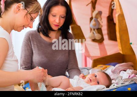 Hebamme, neugeborenes Baby auf postnatale Pflege in der Praxis zu prüfen Stockfoto