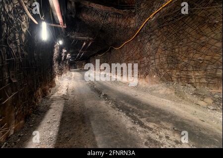 Unterirdische Mine. Unterirdische Straße für den Transport. Die Wände und die Decke des Tunnels sind mit Ankern und Metallgeflecht verstärkt Stockfoto