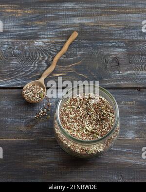Getreidemischung für gesunde Keto-Cracker aus Chia-Samen, Flachs, Sesam, gemahlenen Kürbiskernen in einem Glasgefäß auf Holzboden Stockfoto