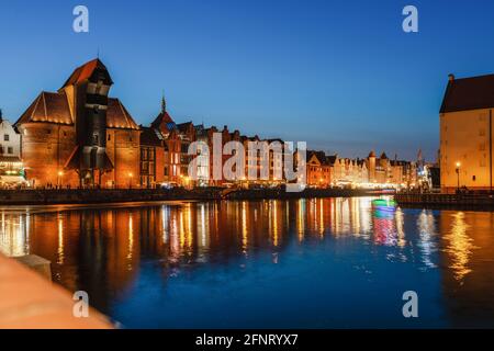 Blick auf die Stadt Danzig bei Nacht am Fluss. Blick auf den berühmten Kran und die Fassaden der alten mittelalterlichen Häuser an der Promenade in Danzig Stadt. Polen. Stockfoto