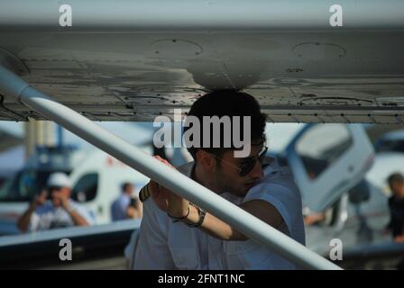 Nahaufnahme eines jungen Piloten, der unter dem Flügel seines Flugzeugs von der Kamera wegschaute und sich auf eine Flugshow vorbereitete. Stockfoto