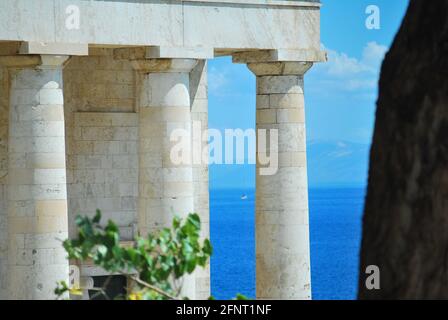 Nahaufnahme von dorischen Säulen bei einem Tempel in Griechenland mit dem blauen Meer im Hintergrund. Stockfoto