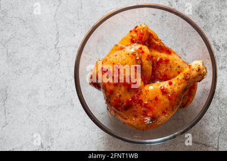 Hähnchen mit Piri- oder Peri-Marinade-Sauce in einer Glasschüssel. Auf einem konkreten Hintergrund Stockfoto