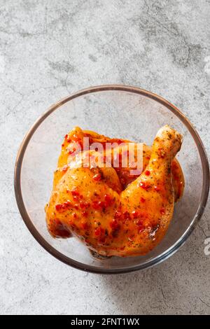 Hähnchen mit Piri- oder Peri-Marinade-Sauce in einer Glasschüssel. Auf einem konkreten Hintergrund Stockfoto