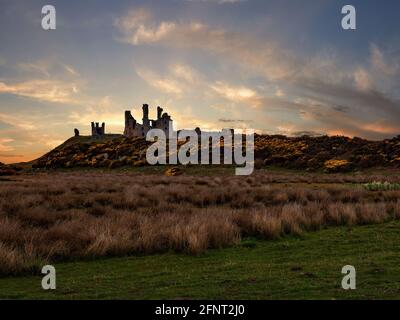 Dunstanburgh Castle liegt auf einer abgelegenen Landzunge in Northumberland, nur einen kurzen Spaziergang vom schönen Fischerdorf Craster entfernt. Hier bei Sonnenaufgang. Stockfoto