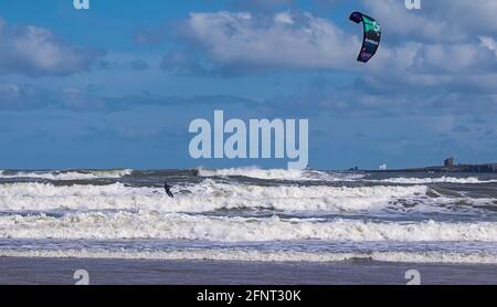 Ein herrlicher sonniger Frühlingstag zum Kitesurfen, mit den starken Winden, die herrliche Breakers erzeugen. Aufgenommen am Bamburgh Beach, Northumberland. Stockfoto