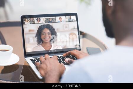 Junger Mann, der mit einer Gruppe von Menschen auf dem Laptop spricht, Geschäftstreffen abgeht, mit Freunden oder Familie während des Gesprächs chattet Stockfoto