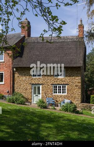 Bijou Stein gebaut Reetgedeckten Hütte mit Blick auf das Grün in dem Dorf Badby, Northamptonshire, Großbritannien Stockfoto