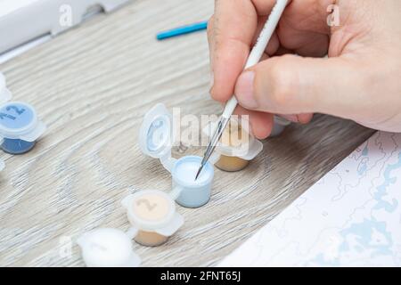 Eine mans Hand mit einem Pinsel zum Zeichnen von Nahaufnahme. Malen für Anfänger.Nahaufnahme, selektiver Fokus. Stockfoto