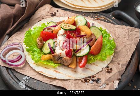 Gegrilltes Fleisch, Pommes Frites, frisches Gemüse und Saucen auf braunem Hintergrund. Vorbereitung von Tacos, Shawarma, Burritos. Nahaufnahme, Seitenansicht. Stockfoto