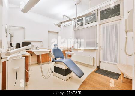 Schreibtisch und Stuhl in der Nähe von professionellen zahnmedizinischen Geräten im Büro platziert Der modernen Klinik Stockfoto