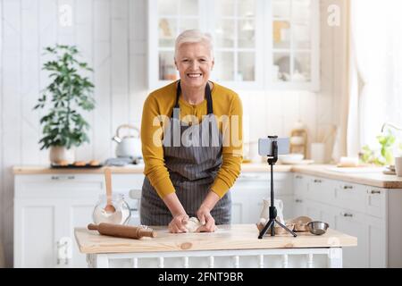 Attraktive ältere Dame, die zu Hause kocht und den Online-Kurs ansieht Stockfoto