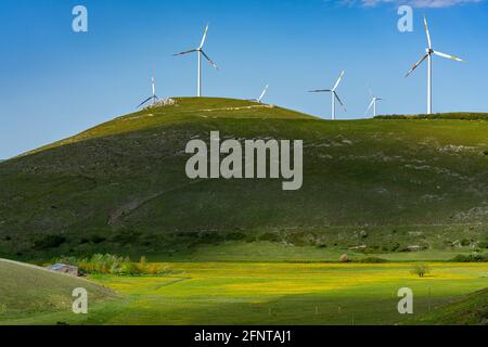 Panorama von grünen und gelben Feldern mit Hügeln und Windkraftanlagen auf der Oberseite. Spiel von Licht und Schatten. Abruzzen, Italien, Europa Stockfoto