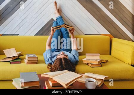 Junge Frau beim Lesen auf dem Sofa im Wohnzimmer Stockfoto