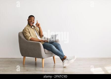Schwarz Kerl Mit Laptop Mit Idee Sitzen Im Stuhl Drinnen Stockfoto