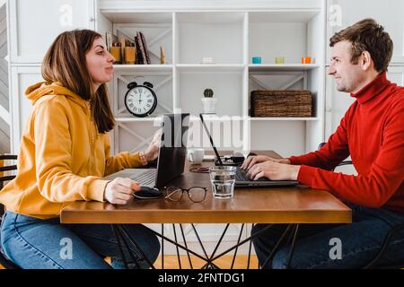 Mann und Frau arbeiten zu Hause im selben Raum. Lachend miteinander Stockfoto
