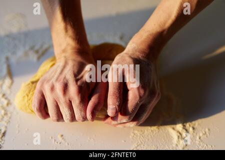 Professioneller männlicher Chefbäcker in grüner Schürze Knetteig für Brot oder Pizza mit Händen. Hausgemachtes Kuchenbacken, Zubereitung einer Torte oder eines leckeren Plätzchens. Bäckerkonzept. Hochwertige Fotos Stockfoto