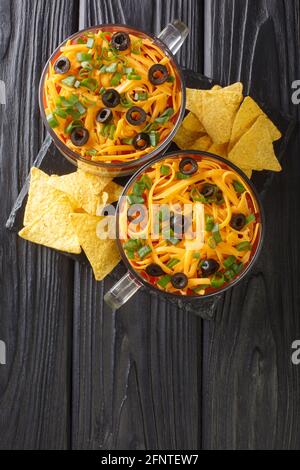 Mexikanischer siebenschichtiger Dip-Salat, serviert mit Chips aus nächster Nähe auf dem Tisch. Vertikale Draufsicht von oben Stockfoto