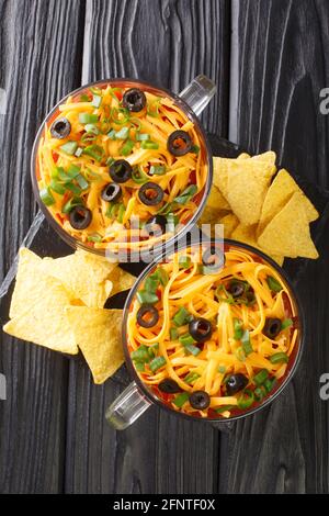 Super Bowl 7 Layer Dip mit Tortilla Chips aus nächster Nähe in das Glas auf dem Tisch. Vertikale Draufsicht von oben Stockfoto