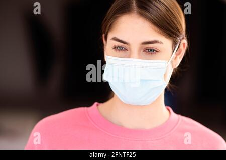 Kopfschuss einer jungen Frau mit grünen Augen und Gesichtsmaske. Stockfoto