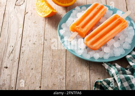 Orangefarbene Eiszapfen auf einem Holztisch Stockfoto