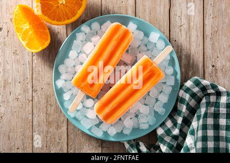 Orangefarbene Eiszapfen auf einem Holztisch Stockfoto