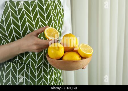 Frau hält eine Holzschale mit reifen Zitronen Stockfoto