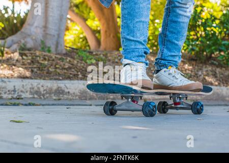 Aufnahme von den Füßen eines Jungen, als sie auf ihrem Skateboard Schlittschuhe fährt. Stockfoto