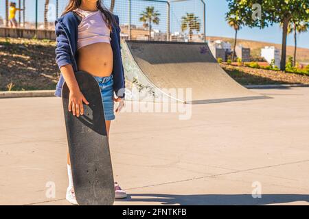 Porträt einer unkenntlichen kaukasischen Skaterin mit ihrem Skateboard In einem Skatepark Stockfoto