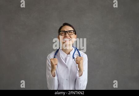 Aufgeregt junge Ärztin zeigt Gewinner Geste klemmende Fäuste Studio Aufnahme Stockfoto
