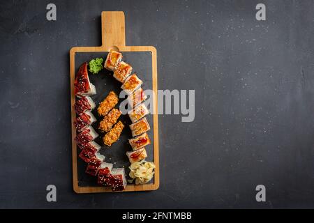 Rolle aus frischem rohem Lachs, geräuchertem Eel, Frischkäse und Avocado im Inneren. Stockfoto