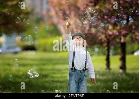 Blonde Kleinkind Kind, niedlichen Jungen in Freizeitkleidung, spielen mit Seifenblasen im Park, laufen glücklich Stockfoto