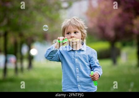 Blonde Kleinkind Kind, niedlichen Jungen in Freizeitkleidung, spielen mit Seifenblasen im Park, laufen glücklich Stockfoto