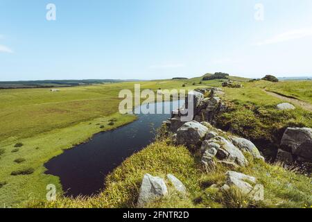 Northumberland UK: Hadriansmauer an einem sonnigen Sommertag in englischer Landschaft auf hohen Klippen (Römische Mauer) errichtet. Blick auf den See Stockfoto