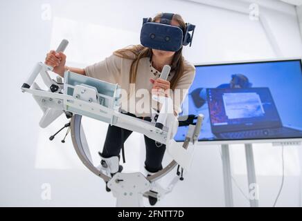 19. Mai 2021, Sachsen-Anhalt, Halle (Saale): Anja Wolf demonstriert den Einsatz eines speziellen Fitnessgeräts mit VR-Brille für die Forschung im neuen Erxleben Digital Healthcare Hub der Universitätsmedizin Halle. Im Dorothea Erxleben Learning Center der Universitätsmedizin wurde ein neuer Gebäudeteil eröffnet. Dort sind drei verschiedene Projekte angesiedelt - sie beschäftigen sich mit der Frage, wie die medizinische Versorgung von Patienten mit informationstechnischen Methoden verbessert werden kann. Quelle: dpa picture Alliance/Alamy Live News Stockfoto