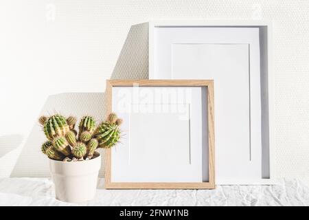 Zwei Holzrahmen und Kaktus auf weißem Tisch. Stockfoto