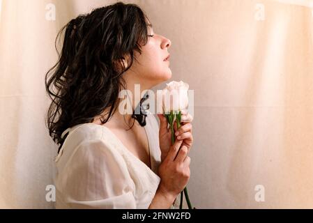 studio Portrait von glühenden jungen Frau hält rosa Rosen mit natürlichen Look. Und natürliches weiches Licht. Poetisches Bild des blühenden Lebens. Augen wegschauen Stockfoto