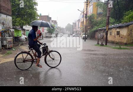 Prayagraj, Uttar Pradesh, Indien. Mai 2021. Prayagraj: Ein Radfahrer benutzt einen Regenschirm, um am Mittwoch, den 19. Mai 2021, vor einer Regendusche in Prayagraj sicher zu sein. Quelle: Prabhat Kumar Verma/ZUMA Wire/Alamy Live News Stockfoto