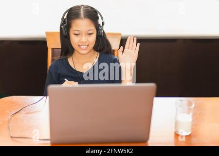 Asiatische Student winkt Hand, während der Kurs über einem Laptop während covid-19. Stockfoto