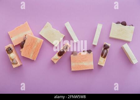 Natürliche handgemachte Seifenstücke flach Lay Zusammensetzung. Viele duftende handgemachte Spa Bio rosa weiße Seifenstücke. Hausgemachte Beauty-Produkte auf lila Stockfoto