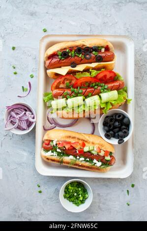 Köstliche frisch gekochte Hot Dogs, voll beladen mit verschiedenen Belägen auf einem Tablett Stockfoto