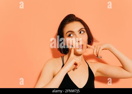 Junge Frau flirtet mit Lippen und Händen in der Nähe des Gesichts Auf orangefarbenem Hintergrund Stockfoto