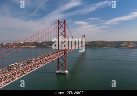 Lange rote mehrstockige Hängebrücke, die Lissabon mit Almada über einen breiten Fluss von der Drohne verbindet. Starker Verkehr auf mehrspurigen Straßen. Stockfoto