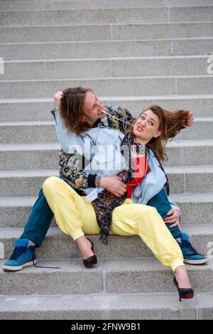 Junges Paar, das auf Stufen sitzt und mit Kaugummi spielt Stockfoto