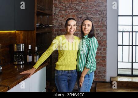 Mittelklasse-Familie in der Küche der Loft-Wohnung, zwei elegante Schwestern von etwa 40. Stockfoto