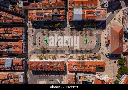 Luftaufnahme des King Pedro IV Platzes, auch bekannt als Rossio. Länglicher Platz mit Wellenmuster, zwei Brunnen und einem zentralen Denkmal. Stockfoto